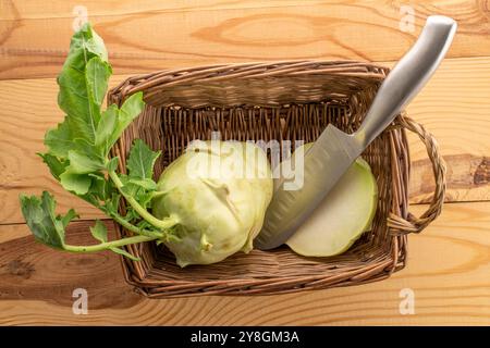 Frischer reifer Kohlrabi-Kohl in einem Korb auf einem Holztisch, Makro, Draufsicht. Stockfoto