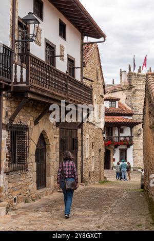 Ein Tourist auf einer kopfsteingepflasterten Straße, umgeben von alten Häusern in der mittelalterlichen kleinen Stadt Santillana del Mar, Kantabrien in Nordspanien Stockfoto