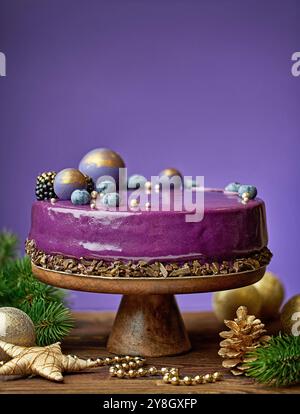 Wunderschöner lila dekorierter Kuchen auf Holztisch und lila Hintergrund Stockfoto
