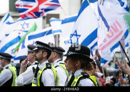 London, Großbritannien. 5. Oktober 2024. Polizeibeamte sehen zu, wie palästinensische Anhänger am 20. Nationalmarsch für Palästina teilnehmen, der ein Jahr seit Beginn des Krieges Israels gegen Gaza und das besetzte Westjordanland markiert, an einer kleinen Gruppe von pro-israelischen Gegenprotestierenden vorbeikommen. Aktivisten forderten, dass Großbritannien die Bewaffnung Israels aufhört, einen sofortigen Waffenstillstand und ein Ende des jüngsten israelischen Krieges gegen den Libanon forderte. Quelle: Ron Fassbender/Alamy Live News Stockfoto