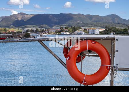 Rote Rettungsleine auf einem Boot in einem Hafen. Stadt und Berge im unscharfen Hintergrund. Blauer Himmel mit weißen Wolken im Spätsommer. Astrakeri, Korfu, Stockfoto