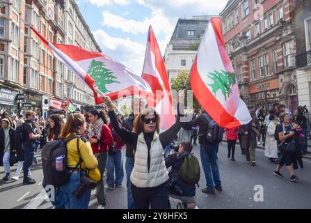 London, Großbritannien. Oktober 2024. Ein Demonstrant hält libanesische Fahnen während der Demonstration. Tausende von Menschen marschierten in Zentral-London in Solidarität mit Palästina und dem Libanon, um den ersten Jahrestag des Krieges zwischen Israel und der Hamas zu feiern, der begann, als die Hamas am 7. Oktober 2023 beim Nova-Musikfestival Israelis tötete und entführte. (Foto: Vuk Valcic/SOPA Images/SIPA USA) Credit: SIPA USA/Alamy Live News Stockfoto