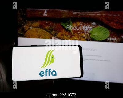 Person mit Smartphone und Logo der European Flavour Association (EFFA) auf dem Bildschirm vor der Website. Schwerpunkt auf dem Display des Telefons. Stockfoto