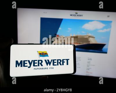 Person mit Smartphone und Logo der Werft Meyer Werft GmbH Co. KG auf dem Bildschirm vor der Website. Schwerpunkt auf dem Display des Telefons. Stockfoto