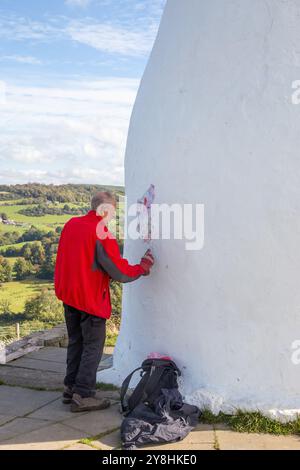 Ein Freiwilliger repariert White Nancy, einen Mann, der auf dem Gritstone Trail auf der Spitze des Kerridge Hill mit Blick auf Bollington, Cheshire, gebaut wurde Stockfoto