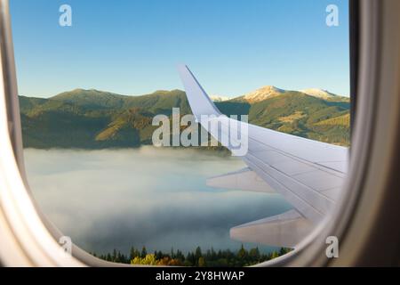 Das Flugzeug fliegt über die Berge, wunderschöne Aussicht vom Fenster Stockfoto