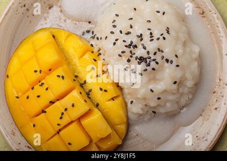 Traditionelles Dessert von Thailand, köstlicher Mango-Kleberreis mit Kokosnussmilch und Sesamsamen auf tropischem Blatt von oben Stockfoto