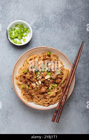 Dan Dan Dan Nudeln serviert mit Essstäbchen und grünen Zwiebeln, traditionelles chinesisches Sichuan-Gericht Stockfoto