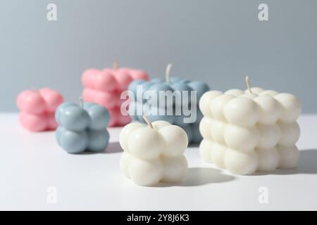 Schöne Bubble Kerzen auf weißem Tisch vor grauem Hintergrund Stockfoto