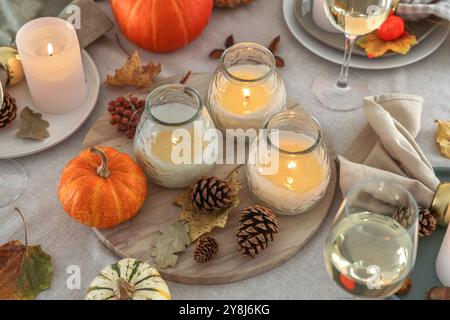 Brennende Kerzen, Weingläser und Herbstdekor auf dem Tisch, Nahaufnahme Stockfoto