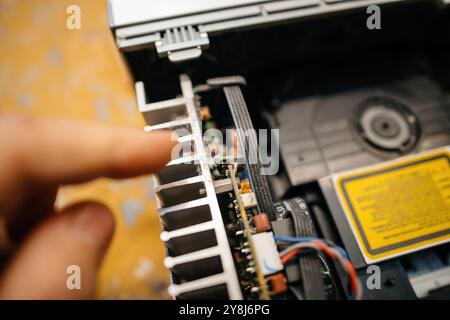 Eine Person zeigt auf das Kühlsystem voller Staub eines alten Elektronikgeräts, hebt dessen Komponenten und Konstruktionsmerkmale hervor, während sie seine Funktionalität untersucht Stockfoto