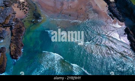 Blick aus der Vogelperspektive auf einen Strand mit klarem blauem Wasser und Sandstrand. Wellen krachen sanft an der Küste und bilden einen schönen Kontrast zum felsigen Formatio Stockfoto