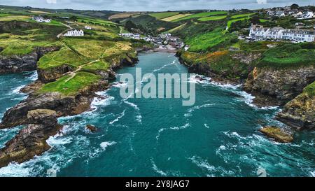 Ein malerischer Blick auf die Küste mit felsigen Klippen, üppigen grünen Hügeln und einem ruhigen blauen Meer. Kleine weiße Häuser umgeben von der Landschaft, eingebettet in das Grün Stockfoto