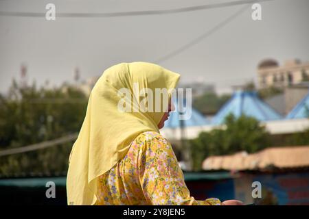 Taschkent, Usbekistan; 16. September 2024: Eine muslimische Frau trägt einen gelben Hijab und passende Kleidung, während sie durch die belebten Straßen von Taschken spaziert Stockfoto