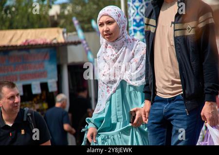 Taschkent,Usbekistan;September,16,2024:Eine junge muslimische Frau, bescheiden gekleidet in einem Hidschab, spaziert durch die hektischen Menschenmassen auf den Straßen von Taschkent, Stockfoto