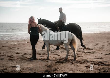 Reitspaar am Strand, Sommerreiter Mann und Frau Stockfoto