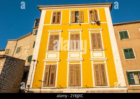 Gelbes Wohngebäude in der Altstadt von Sibenik bei Sonnenuntergang in Dalmatien in Kroatien. Stockfoto