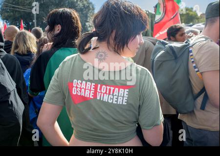 Rom, Italien. Oktober 2024. Ein Demonstrant trägt ein T-Shirt mit dem Slogan „Dare to fight, Dare to win“ während der pro-palästinensischen Demonstration zwei Tage vor dem Jahrestag des 7. Oktober in Rom. Tausende von Menschen aus Rom und verschiedenen Teilen Italiens nahmen zwei Tage vor dem Jahrestag des 7. Oktober an der propalästinensischen Demonstration Teil, obwohl das Polizeipräsidium von Rom Demonstrationen verboten hatte. Quelle: ZUMA Press, Inc./Alamy Live News Stockfoto