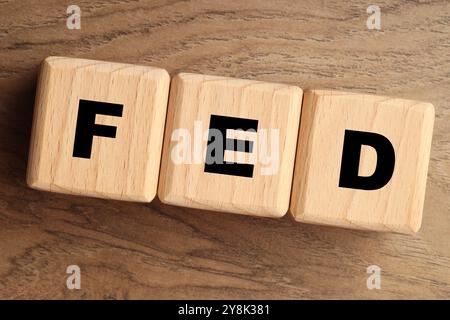 Würfel mit den Buchstaben Fed (Federal Reserve System) auf Holztisch, Draufsicht Stockfoto