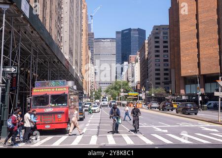NEW YORK, NEW YORK, USA – 20. AUGUST 2024: Straßenszene, in der Menschen über eine Kreuzung auf der Park Avenue in New York City spazieren. Stockfoto