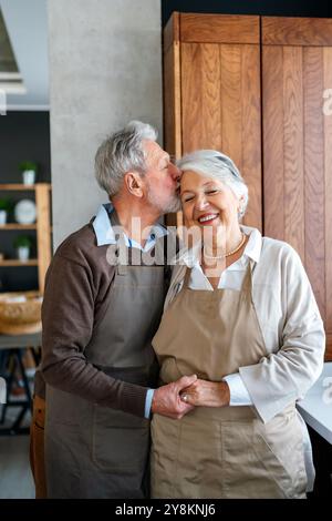 Glückliches Seniorenpaar, das miteinander kommuniziert, während es Spaß in der Küche hat Stockfoto