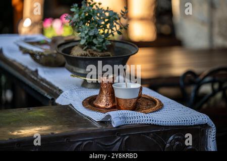 Auf einem Sideboard, das mit einer weißen Tischdecke bedeckt ist, gibt es einen traditionellen türkischen Kaffee mit einer Kanne und einem Tablett. Stockfoto