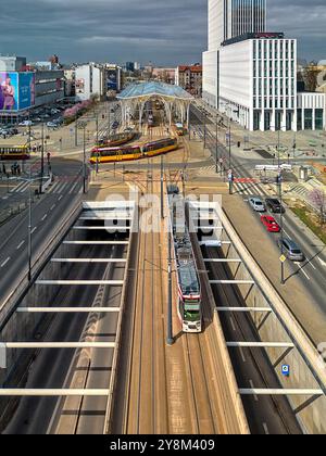 Titel: Luftaufnahme eines modernen Straßenbahnhofs in Łódź, Polen mit mehreren Straßenbahnen, Glasdach und städtischer Infrastruktur im Herzen der Stadt Stockfoto