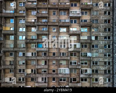 Nahaufnahme einer Wohnblockfassade aus sowjetischer Zeit in Łódź, Polen, mit einem Gitter aus verwitterten Betonbalkonen und Fenstern Stockfoto