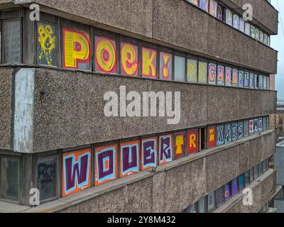 Brutalistisches Gebäude, bedeckt mit farbenfrohen Graffiti auf Fenstern und Fassade in einem dicht besiedelten Stadtgebiet an einem bewölkten Tag in Łódź, Polen Stockfoto