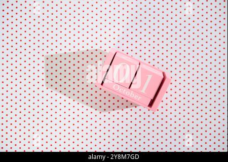Ein rosafarbener Blockkalender, der den 1. Oktober auf einem weißen Polka Dot-Hintergrund anzeigt und eine verspielte und moderne Ästhetik schafft. Ideal für Herbst- oder Veranstaltungsbilder Stockfoto