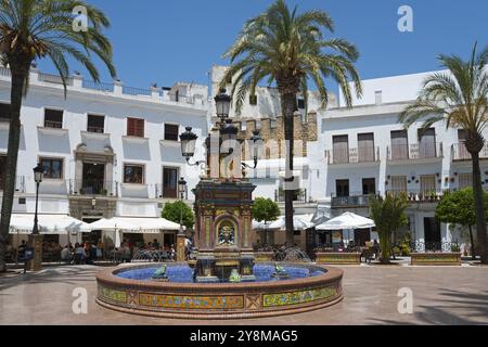 Ein zentraler Brunnen auf einem sonnigen platz umgeben von weißen Gebäuden und Palmen, Brunnen mit Azulejos, Plaza de Espana, Platz, Altstadt, Vejer de Stockfoto