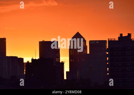 Oranger Himmel eines herbstlichen Sonnenuntergangs über East London mit Blick auf Canary Wharf Stockfoto