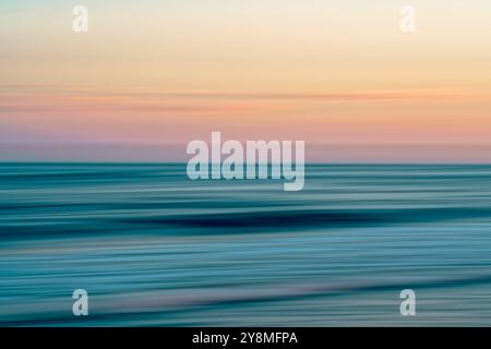 Sanfte, fließende Wellen fügen sich nahtlos in die ruhigen Farben des Horizonts ein. Stockfoto