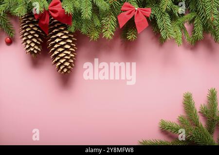 Flaches Lay-Design der Weihnachtskarte aus Tannenzweigen Schleifen und Zapfen auf rosa Hintergrund. Platz für Text Stockfoto