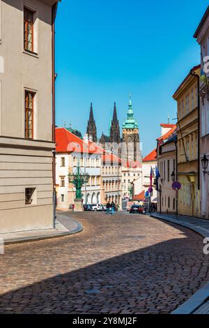 Die kopfsteingepflasterte Straße schlängelt sich durch historische Gebäude in Prag mit dem Veitsdom. Die Straße führt vorbei an historischen Gebäuden in Prag und zeigt Stockfoto