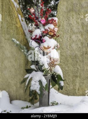 Schneebedeckte Blumenarrangements auf dem Friedhof Stockfoto