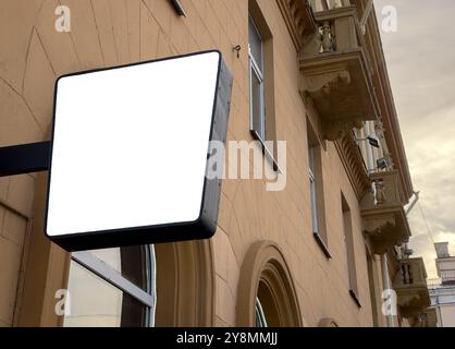 Außenschilder-Mockup auf einer Stadtstraße. Leeres und leeres Brett, das an der Außenseite eines Geschäfts oder Büros hängt. Isolierte weiße Vorlage für Werbung Stockfoto
