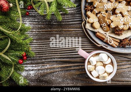 Flach Weihnachten Hintergrund von pink Becher mit heißer Schokolade und Marshmallows, Branche und Fach Mit Gingerbread Man Cookies auf hölzernen Tisch Fichte Stockfoto