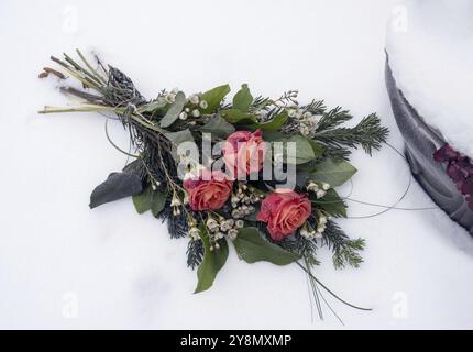 Schneebedeckte Blumenarrangements auf dem Friedhof Stockfoto