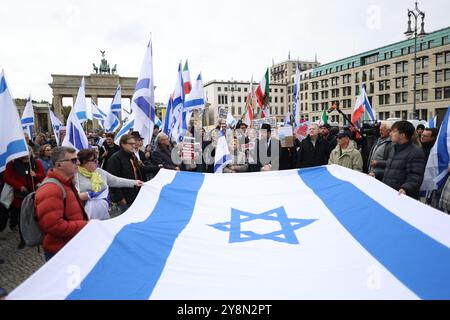 Berlin, Deutschland. Oktober 2024. Die Teilnehmer der pro-israelischen Demonstrationen halten eine große israelische Flagge zusammen. Die pro-israelische Demonstration "gemeinsam gegen die Hamas" Verbrechen gegen Israelis und Palästinenser. Für die Freilassung der Geiseln und das Ende der Hamas-Herrschaft in Gaza." Wird am Pariser Platz in der Nähe des Brandenburger Tors anlässlich des ersten Jahrestages des Angriffs der Hamas auf Israel stattfinden. Quelle: Jörg Carstensen/dpa/Alamy Live News Stockfoto