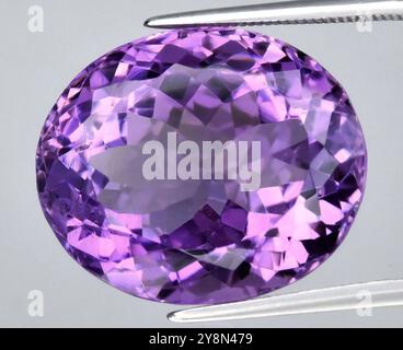 Exquisiter natürlicher Amethyst-Edelstein mit Oval Cut, der in leuchtenden Lila-Tönen und makelloser Klarheit glänzt. Stockfoto