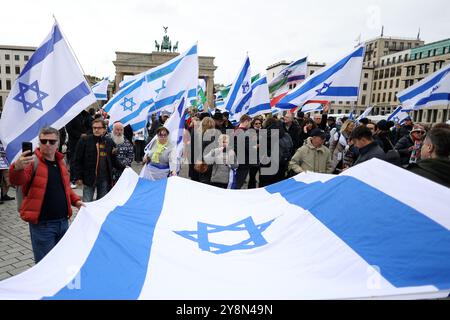 Berlin, Deutschland. Oktober 2024. Die Teilnehmer der pro-israelischen Demonstrationen halten eine große israelische Flagge zusammen. Die pro-israelische Demonstration "gemeinsam gegen die Hamas" Verbrechen gegen Israelis und Palästinenser. Für die Freilassung der Geiseln und das Ende der Hamas-Herrschaft in Gaza." Wird am Pariser Platz in der Nähe des Brandenburger Tors anlässlich des ersten Jahrestages des Angriffs der Hamas auf Israel stattfinden. Quelle: Jörg Carstensen/dpa/Alamy Live News Stockfoto