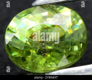 Exquisiter natürlicher Peridot-Edelstein mit leuchtenden Grüntönen und kompliziertem Schnitt. Stockfoto