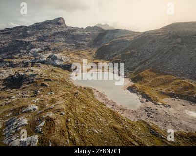 Drohnenblick auf die Savognin Berge in der Schweiz bei Sonnenuntergang mit Blick auf zerklüftete Gipfel und Täler, die in goldenes Licht getaucht sind Stockfoto