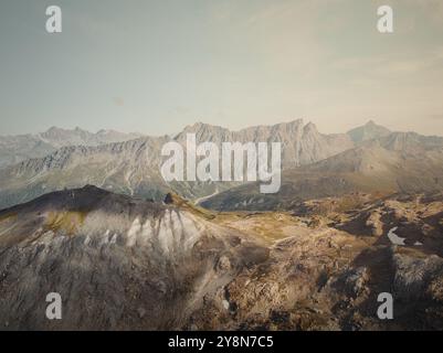 Drohnenblick auf die Savognin Berge in der Schweiz bei Sonnenuntergang mit Blick auf zerklüftete Gipfel und Täler, die in goldenes Licht getaucht sind Stockfoto