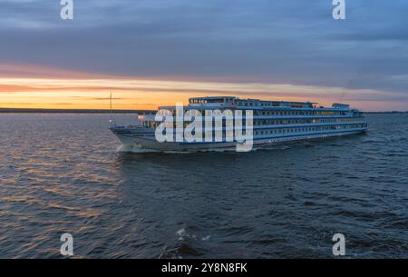 Wolga Fluss, Russland, 06.16.2024 Kreuzfahrtschiff „Andrey Rublev“ segelt entlang der Wolga vor dem Hintergrund des Sonnenuntergangs Stockfoto