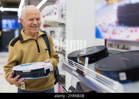 Senor man Rentner kauft Roboter-Staubsauger im Showroom eines Elektrogerätegeschäfts Stockfoto