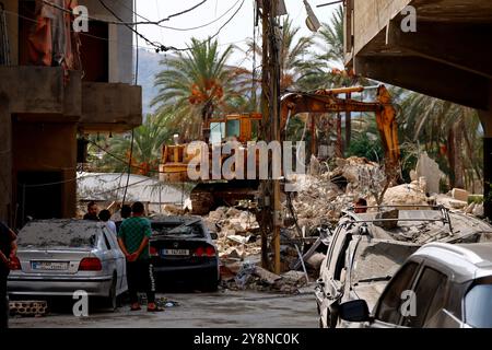 Jiyeh, Libanon. Oktober 2024. Libanesen beobachten, wie eine raupe bei der Suche nach Überlebenden im südlibanesischen Dorf Jiyeh Schutt eines flachen Gebäudes beseitigt, das von einem israelischen Luftangriff angegriffen wurde. Quelle: Stringer/dpa/Alamy Live News Stockfoto