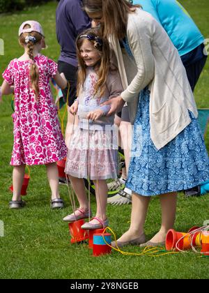 Ein kleines Kind lernt, wie man Stelzenspaziergang während eines Zirkus-Workshops in Bude, Cornwall, Großbritannien Stockfoto