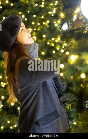 Fröhliche Pariser Frau, die Weihnachtsbaumschmuck im Winter in Paris bewundert Stockfoto